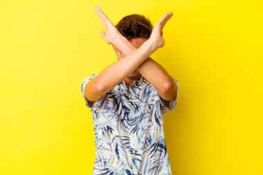 Sarı arka planda izole genç beyaz adam iki kolu çapraz tutuyor, inkar kavramı.