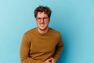 Mavi arka planda gözlük takan genç beyaz bir adam karaciğer ağrısı ve mide ağrısı çekiyor..