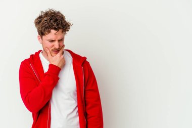 Beyaz arka planda izole edilmiş genç beyaz bir adam kafasının arkasına dokunuyor, düşünüyor ve bir seçim yapıyor..