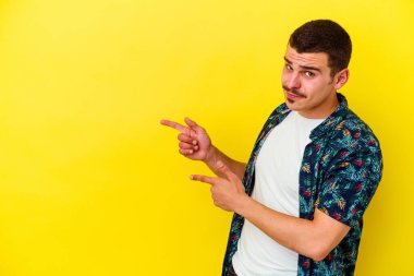 Sarı arka planda izole edilmiş genç, beyaz bir adam işaret parmağıyla bir fotokopi alanını işaret ederek heyecan ve arzuyu ifade ediyor..