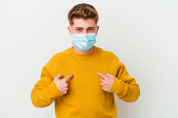 Young man wearing a mask for coronavirus isolated on white background surprised pointing with finger, smiling broadly.
