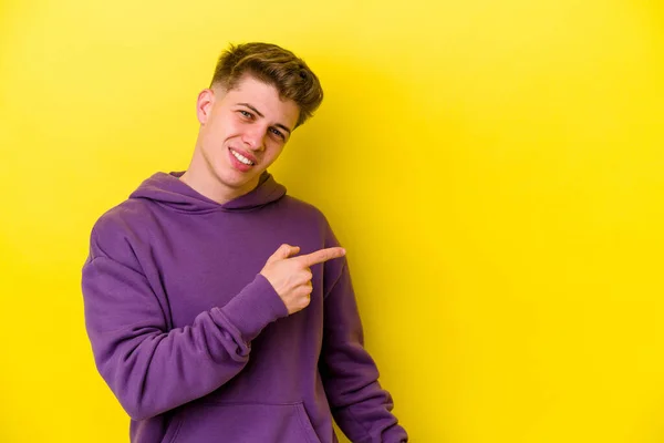 Joven Hombre Caucásico Aislado Sobre Fondo Amarillo Sonriendo Señalando Lado —  Fotos de Stock