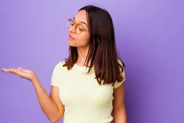 Genç melez kadın, kafası karışmış ve omuz silkmiş bir şekilde bir kopya alanı tutmak için izole edilmiş..