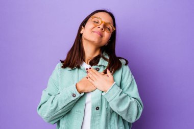 Karma ırktan genç bir kadın, dost canlısı bir ifadeye sahip, avuçlarını göğsüne bastırıyor. Aşk konsepti.