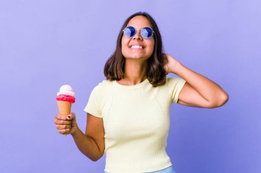 Genç melez kadın dondurma yiyor. Kendine güveniyor, elleri başının arkasında..