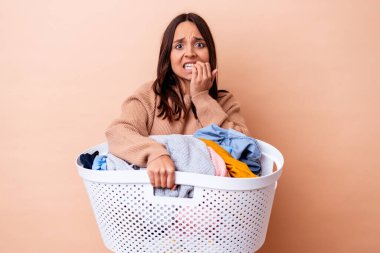 Çamaşır tutan genç melez kadın tırnak yiyor, gergin ve endişeli..