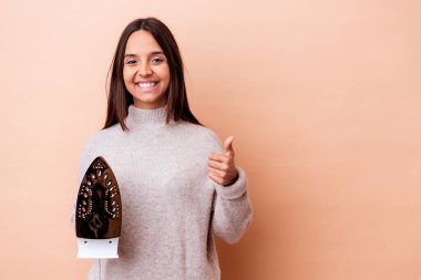 Genç melez bir kadın elinde demir bir izole edilmiş gülümseme ve baş parmağını kaldırıyor.