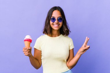 Genç melez kadın dondurma yiyor zafer işareti gösteriyor ve gülümsüyor..