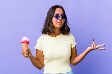 Genç melez bir kadın dondurma yiyor şüpheyle ve omuz silkerek jesti sorguluyor..