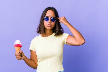 Dondurma yiyen genç melez kadın bir işe odaklanmış, işaret parmaklarını işaret ediyor..