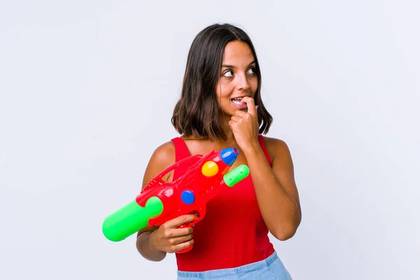 Jovem Mista Segurando Uma Arma Água Isolado Relaxado Pensando Algo — Fotografia de Stock