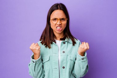 Genç melez kadın kameraya yumruk gösteriyor, agresif yüz ifadesi var..