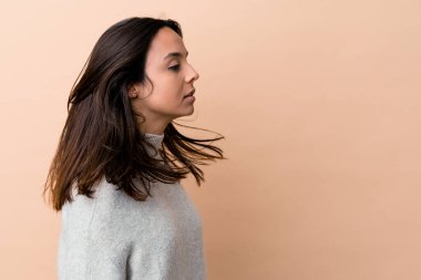 Genç Hintli kadın saçlarını bej arka planda tek başına taşıyor.