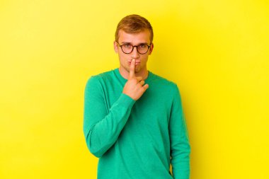 Kafkasyalı genç adam sarı arka planda izole edilmiş düşünüyor ve yukarı bakıyor, yansıtıyor, düşünüyor, hayal kuruyor..