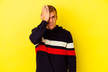 Sarı arka planda izole edilmiş genç beyaz bir adam bir şeyi unutuyor. Alnına avuç içi ve gözlerini kapayarak vuruyor..