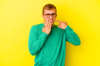 Sarı arka planda izole genç beyaz adam güçlü bir diş ağrısı, azıdişi ağrısı var..