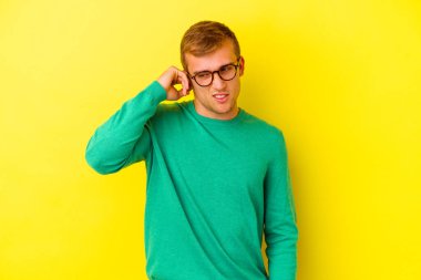 Sarı arka planda izole edilmiş genç beyaz bir adam parmaklarıyla kulaklarını kapatıyor, gürültülü bir ortam yüzünden stresli ve çaresiz..