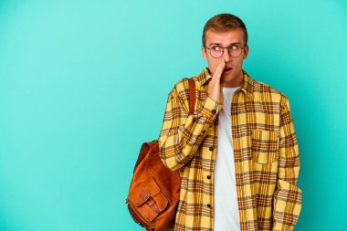 Kafkasyalı genç bir öğrenci mavi arka planda izole edilmiş bir şekilde gizli bir sıcak fren haberi veriyor ve yana bakıyor.