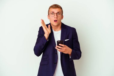 Beyaz arka planda izole edilmiş cep telefonu tutan genç iş adamı şaşırdı ve şok oldu..