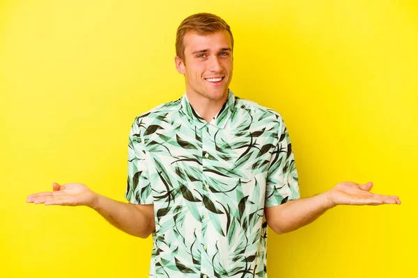Young Caucasian Man Isolated Yellow Background Makes Scale Arms Feels — Stock Photo, Image