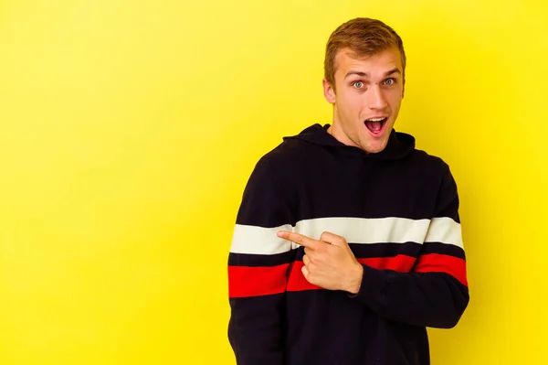 Jovem Caucasiano Isolado Fundo Amarelo Sorrindo Apontando Para Lado Mostrando — Fotografia de Stock