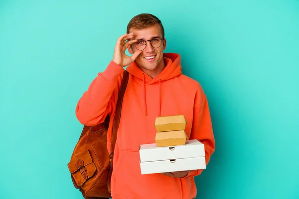 Młody Student Kaukaski Człowiek Gospodarstwa Hamburgery Pizze Izolowane Niebieskim Tle — Zdjęcie stockowe