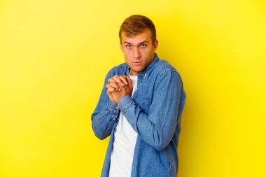 Sarı arka planda izole edilmiş genç beyaz adam korkmuş ve korkmuş..