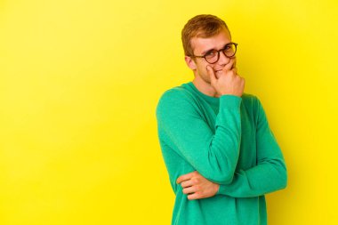 Sarı arka planda izole edilmiş genç beyaz adam gülüyor, kaygısız, doğal duygu..