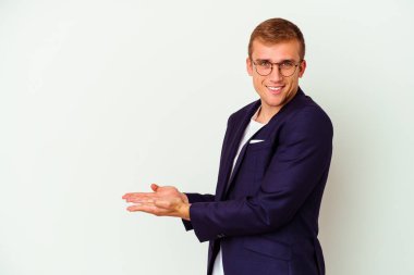 Beyaz arka planda izole edilmiş beyaz tenli genç bir adam palmiye üzerinde bir kopya alanı tutuyor..