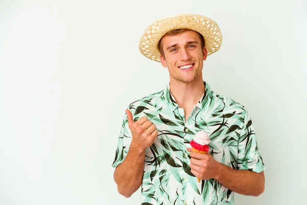 若い白人男性が夏服を着て白い背景に孤立したアイスクリームを保持笑顔と親指を上げる — ストック写真