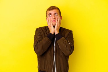 Kafkasyalı genç adam sarı arka planda izole edilmiş sızlanıyor ve ağlıyordu..