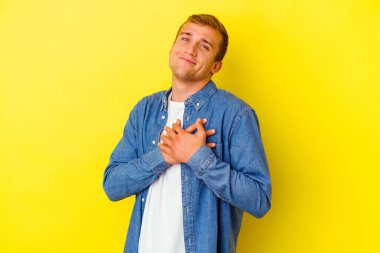 Sarı arka planda izole edilmiş beyaz bir genç, dost canlısı bir ifadeye sahip, avuçlarını göğsüne bastırıyor. Aşk konsepti.