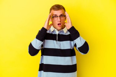 Sarı arka planda izole edilmiş genç beyaz adam şaşırdı ve şok oldu..