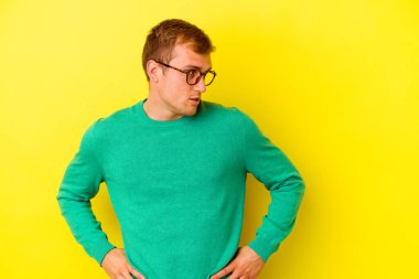 Sarı arka planda izole edilmiş genç beyaz adam gülümseyen, neşeli ve keyifli görünüyor..