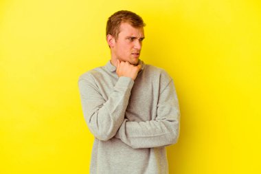 Sarı arka planda izole edilmiş genç beyaz bir adam virüs veya enfeksiyon yüzünden boğazında ağrı hissediyor..