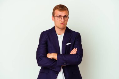 Beyaz arka planda izole edilmiş genç beyaz bir adam kameraya alaycı bir ifadeyle bakıyor..