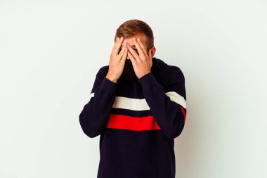 Beyaz arka planda izole edilmiş virüs maskesi takan genç beyaz bir adam korkmuş ve gergin parmaklarıyla göz kırp..