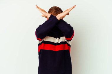 Beyaz arka planda izole edilmiş virüs maskesi takan genç beyaz bir adam iki kolu çapraz tutuyor, inkar kavramı.