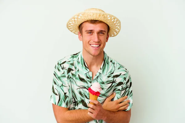 若い白人男性が夏服を着て 白い背景に孤立したアイスクリームを持って笑って楽しんでいます — ストック写真