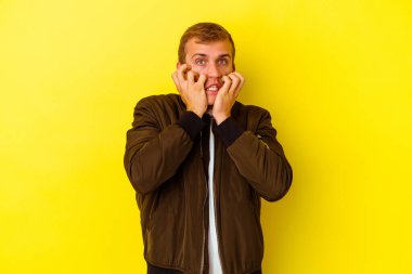 Kafkasyalı genç adam sarı arka planda izole edilmiş, ağlıyor, bir şeyden memnun değil, acı ve kafa karışıklığı kavramı..