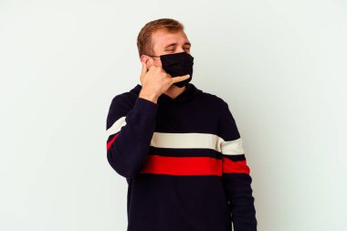 Beyaz arka planda izole edilmiş virüs maskesi takan genç beyaz bir adam parmakları olan bir cep telefonu hareketi gösteriyor..