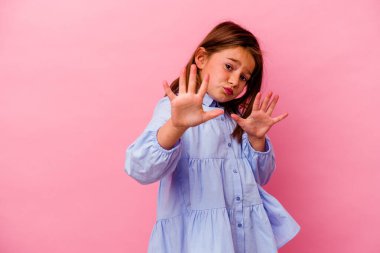 Pembe arka planda izole edilmiş küçük beyaz kız iğrenme belirtisi gösteren birini reddediyor..