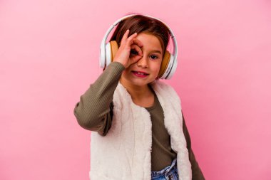 Pembe arka planda izole edilmiş müzik dinleyen küçük beyaz kız..
