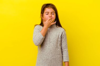 Sarı arka planda izole edilmiş küçük beyaz kız esniyor. Ağzı eliyle kapatan yorgun bir hareket sergiliyor..