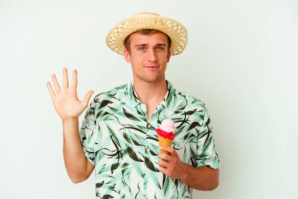 若いですCaucasian男身に着けています夏服とホワイトの背景に隔離されたアイスクリームを保持笑顔番号5とともに指 — ストック写真