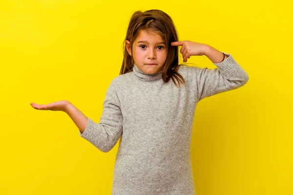 黄色の背景に孤立した小さな白人の女の子を保持し 手に製品を示す — ストック写真