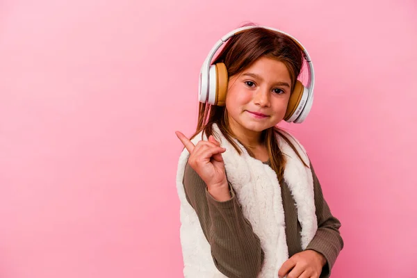 Menina Caucasiana Ouvindo Música Isolada Fundo Rosa Sorrindo Apontando Para — Fotografia de Stock