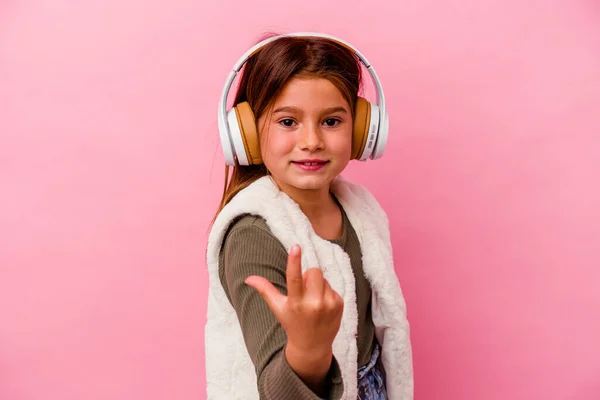 Pequeña Chica Caucásica Escuchando Música Aislada Sobre Fondo Rosa Señalándote — Foto de Stock