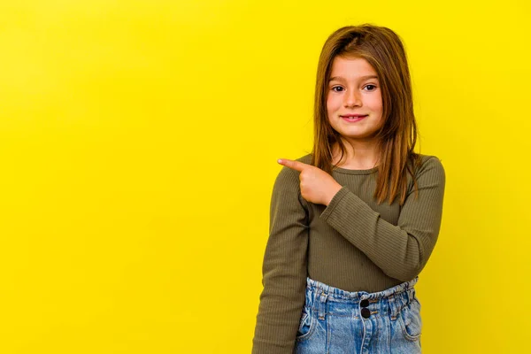 stock image Little caucasian girl isolated on yellow background smiling and pointing aside, showing something at blank space.