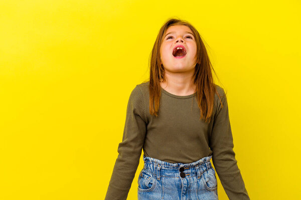 Little caucasian girl isolated on yellow background shouting very angry, rage concept, frustrated.